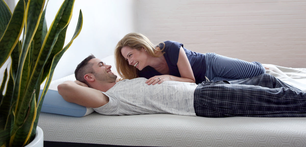 man and woman couple lying on a bear mattress smiling together